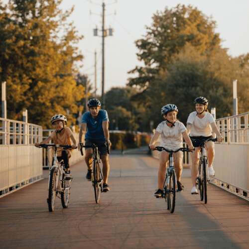 Famille à vélo sur une passerelle, au levée du soleil